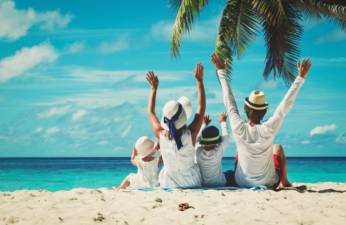 happy family with two kids hands up on beach